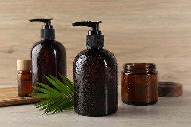 Photo of Shampoo bottles, essential oil, hair mask and green leaf on white wooden table