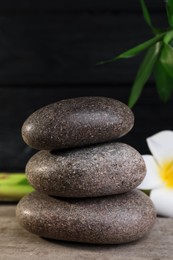 Stacked spa stones, bamboo and flower on wooden table, closeup