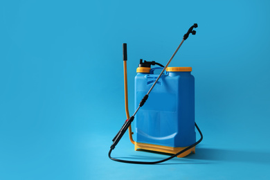Manual insecticide sprayer on blue background, space for text. Pest control