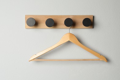 Rack with empty wooden clothes hanger on white wall