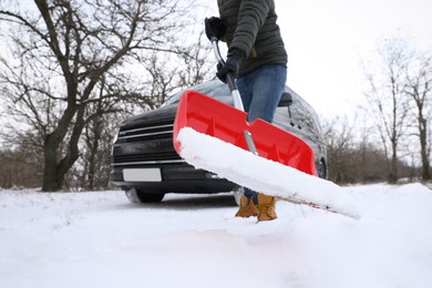 Photo of Man removing snow with shovel near car outdoors on winter day, closeup