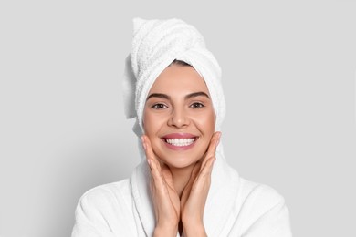 Photo of Young woman in bathrobe with towel on light grey background. Spa treatment