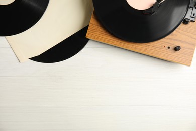 Vintage vinyl records and turntable on white wooden background, flat lay. Space for text