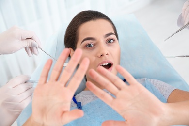 Young woman scared of dental examination in clinic