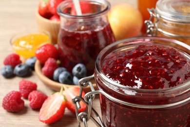 Photo of Jars with different jams and fresh fruits on table, closeup. Space for text