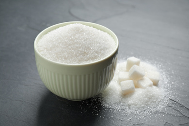 Photo of Granulated sugar in bowl on dark table