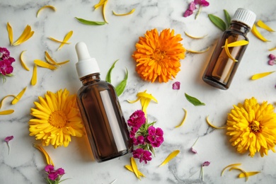 Flat lay composition with essential oils and flowers on marble background