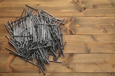 Photo of Many metal nails on wooden background, flat lay. Space for text
