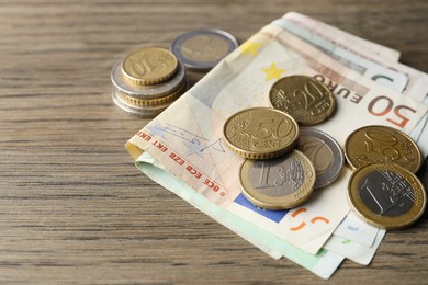 Euro banknotes and coins on wooden table, closeup