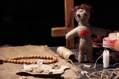 Voodoo doll with pins in heart and ceremonial items on black table