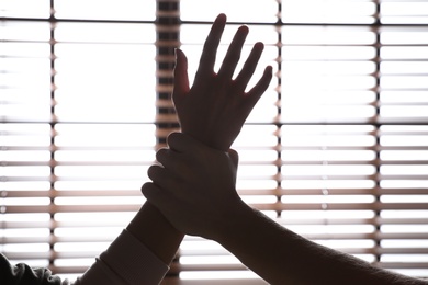 Man grabbing woman's hand near window, closeup. Stop sexual assault