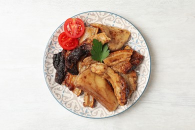 Tasty fried pork lard with parsley and tomatoes on white wooden table, top view