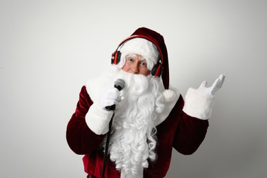 Santa Claus with headphones and microphone on light background. Christmas music