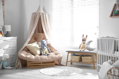 Beautiful baby room interior with comfortable armchair and bench near window