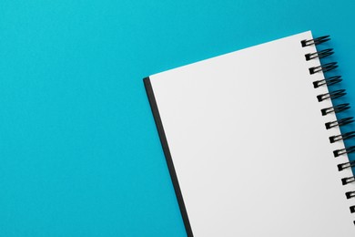 Blank notebook on light blue background, top view. Space for text