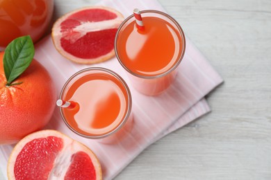 Tasty freshly made grapefruit juice and fruits on white wooden table, flat lay
