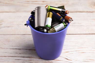 Image of Used batteries in bucket on white wooden table