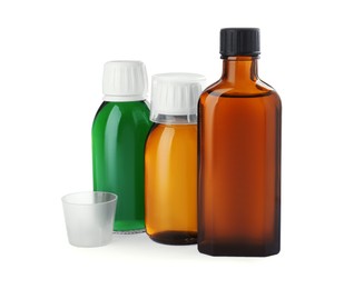 Photo of Bottles of syrups with measuring cups on white background. Cough and cold medicine