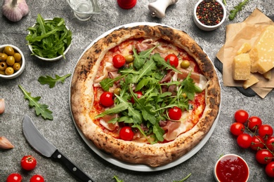 Tasty pizza with meat and arugula on grey table, flat lay