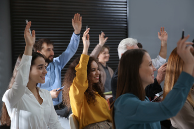People raising hands to ask questions at seminar in office