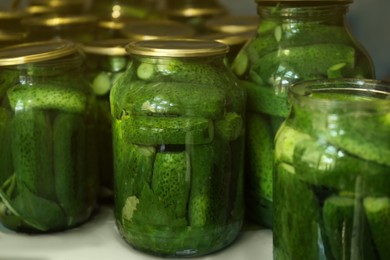 Glass jars with pickled cucumbers on table