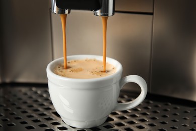 Espresso machine pouring coffee into cup, closeup