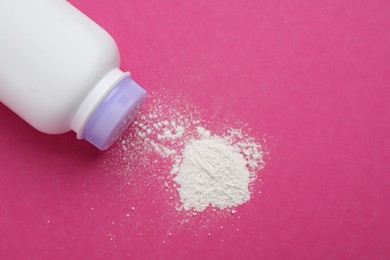 Photo of Bottle and scattered dusting powder on pink background, top view. Baby cosmetic product