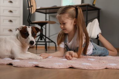 Cute little girl with her dog on floor at home. Childhood pet