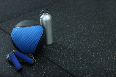 Blue medicine ball, bottle and skipping rope on floor, space for text