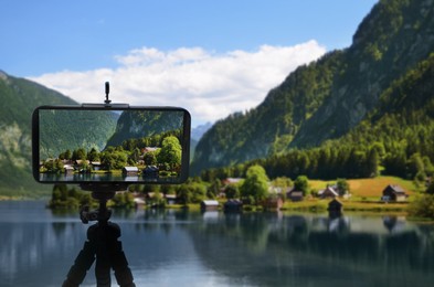 Taking photo of beautiful mountain landscape with smartphone mounted on tripod