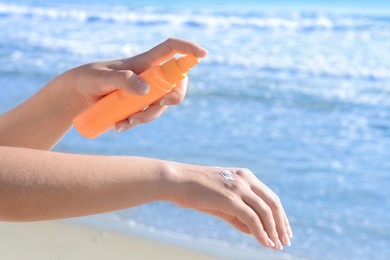 Photo of Woman applying sun protection cream on her hand at beach, closeup