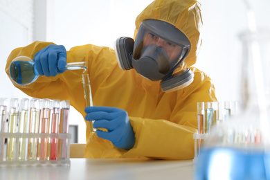 Scientist in chemical protective suit pouring reagent into test tube at laboratory. Virus research