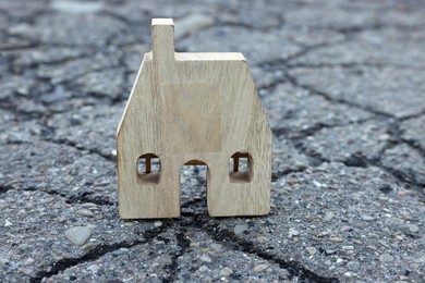 Wooden house model on cracked asphalt. Earthquake disaster