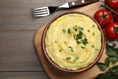Photo of Bowl of freshly cooked mashed potatoes with parsley served on wooden table, flat lay. Space for text