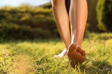 Woman walking barefoot on green grass outdoors, closeup. Space for text