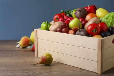Crate full of different vegetables and fruits on wooden table, closeup. Harvesting time