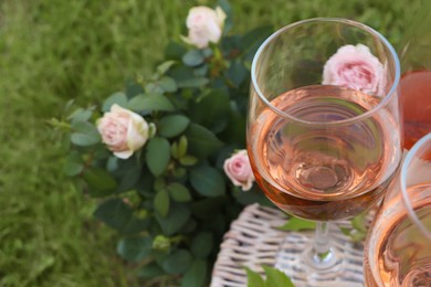 Glasses of delicious rose wine on picnic basket outdoors, closeup. Space for text