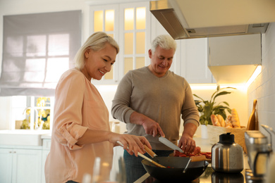 Mature couple cooking food together in kitchen