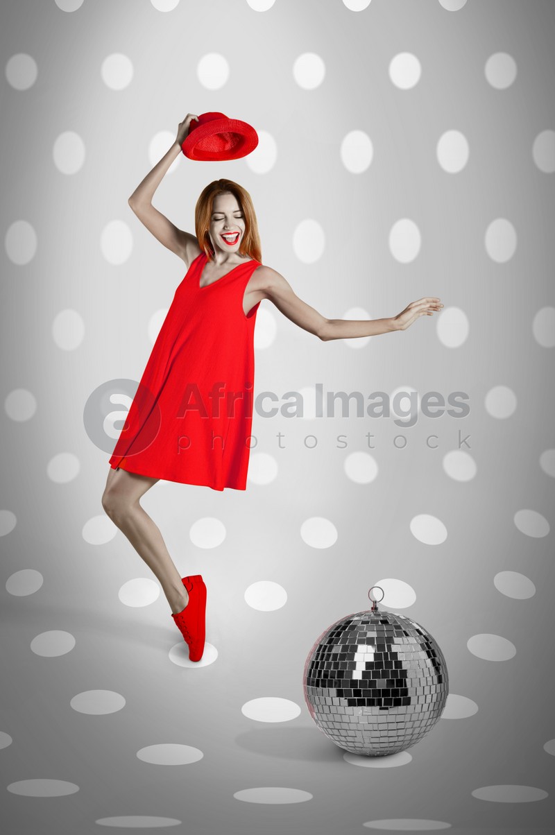 Beautiful young woman dancing near disco ball on spotted background. Bright stylish design