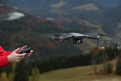 Woman operating modern drone with remote control in mountains, closeup