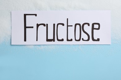 Paper with word Fructose and sugar on light blue background, flat lay. Space for text