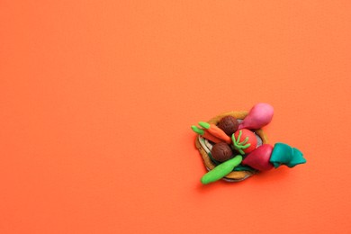 Photo of Different plasticine vegetables on orange background, top view with space for text. Children's handmade ideas