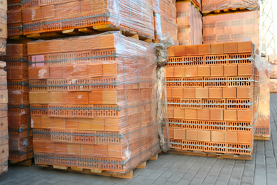 Pallets with red bricks outdoors. Building materials wholesale