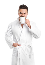 Handsome man in bathrobe drinking coffee on white background