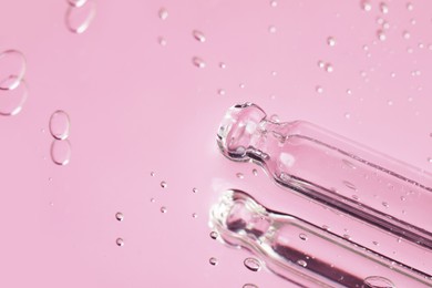 Photo of Pipettes near serum drops on beautiful mirror, closeup with space for text. Toned in pink