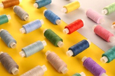 Set of different sewing threads on color background