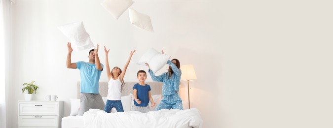 Happy family playing with pillows in bedroom, space for text. Banner design