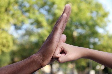 African American man stopping woman's fist outdoors, closeup. Antiracism concept