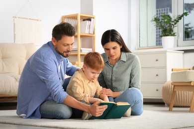 Photo of Happy family reading book together on floor in living room at home