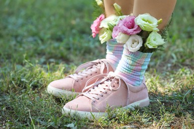 Woman standing on green grass with flowers in socks, closeup